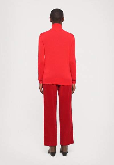 Red turtleneck sweater with long sleeves, shown from the back, paired with wide-leg red corduroy pants and brown heeled shoes.