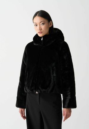 Zwarte faux fur jas met een capuchon, ritssluiting en brede boorden. Zachte textuur, cropped ontwerp, met twee zijzakken.