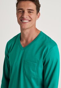 Langsleeve, V-hals shirt in helder turquoise, met een borstzak en zachte, gestructureerde stof. Casual ontwerp geschikt voor dagelijks gebruik.