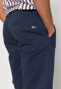 Námořnické modré šortky vyrobené z bavlny, s bočními kapsami a jednou zadní kapsou, s malým značkovým logem v červené, bílé a modré na zadní straně.