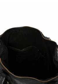 Sac à main en cuir noir avec une fermeture éclair ouverte montrant un intérieur vide et des poches intérieures sur un fond blanc.