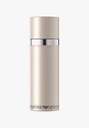 Bouteille cylindrique beige et haute avec une bande argentée près du dessus et le logo "EMPORIO ARMANI" en bas.
