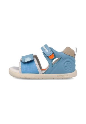Sandalia infantil azul y beige con correas ajustables de velcro, puntera abierta y suela acolchada diseñada para comodidad y soporte.