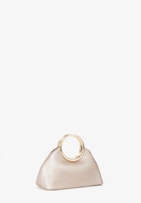 Bolso de mano metálico dorado con forma triangular, acabado brillante y un asa circular dorada. Textura suave y diseño minimalista.