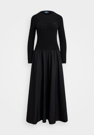 Robe noire avec un haut texturé en tricot torsadé et une jupe fluide et froncée. Encolure ronde et manches longues.