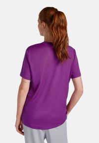 Camiseta morada de manga corta con cuello redondo y corte relajado. Textura suave, vista trasera que muestra un diseño sencillo y la longitud de las mangas.