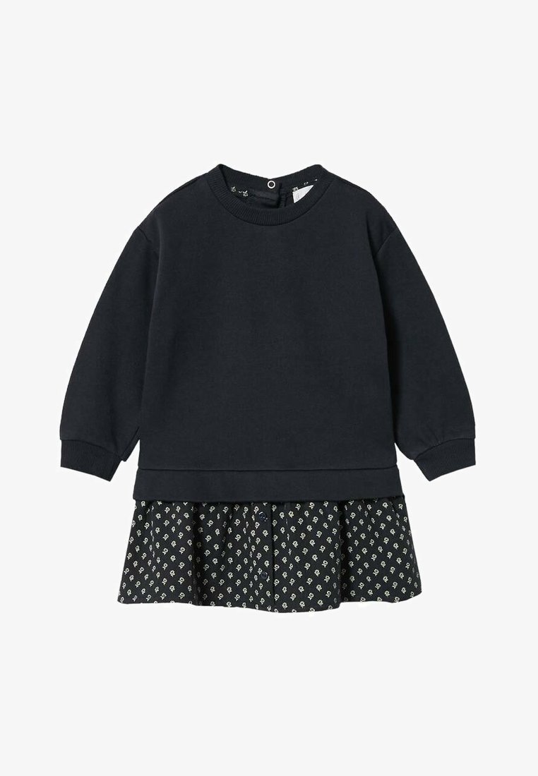 Zwarte sweatshirt met lange mouwen, met een gelaagd ontwerp, gecombineerd met een zwarte rok versierd met kleine witte bloemmotieven.