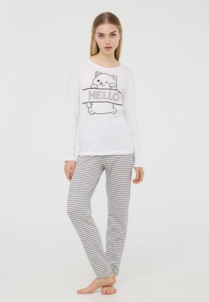 Maglietta bianca a maniche lunghe con grafiche di un gatto e testo "HELLO", abbinata a pantaloni da pigiama a righe grigie e bianche con vestibilità slim.