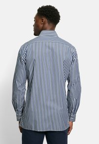 Camicia a righe blu navy e bianca, con colletto button-down, maniche lunghe e orlo dritto. Realizzata in tessuto morbido con una vestibilità su misura.