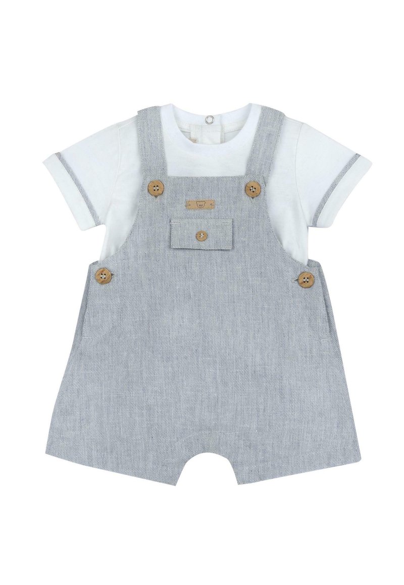 Salopette rayée grise avec boutons en bois, poche avant et jambes courtes, associée à une chemise blanche à manches courtes avec des accents gris.