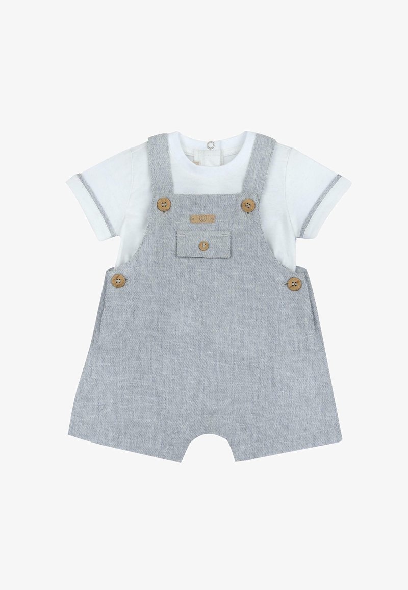 Salopette rayée grise avec boutons en bois, poche avant et jambes courtes, associée à une chemise blanche à manches courtes avec des accents gris.