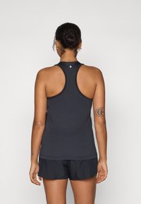 Top sport negru fără mâneci cu un design tip racerback, realizat dintr-un material texturat. Are un mic logo la gâtul din spate, asortat cu pantaloni scurți negri.