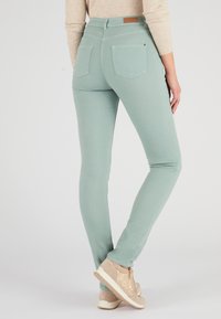 Vaqueros skinny de color verde menta, confeccionados en tela elástica, que presentan dos bolsillos traseros y un parche de cuero con la marca en la cintura.