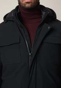 Czarna kurtka z zamkiem z przodu, dwoma kieszeniami na piersi i kapturem. Charakteryzuje się gładką teksturą, dopasowanym fasonem i bordowym golfem pod spodem.