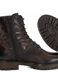 Bruine leren enkelboot met een ritssluiting, ronde neus, metalen veterogen en een gestructureerde rubberen zool met een profielpatroon.