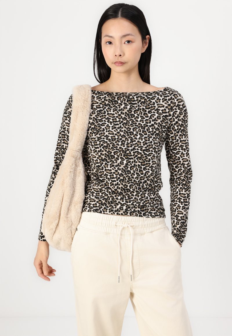 T-shirt à manches longues imprimé léopard en beige et noir, associé à un pantalon beige à taille élastique et un sac épaule en fausse fourrure beige.
