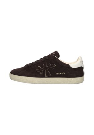 Zapatilla negra de ante de perfil bajo con lengüeta blanca en el talón y logo en el lateral, suela beige texturizada con texto en relieve.