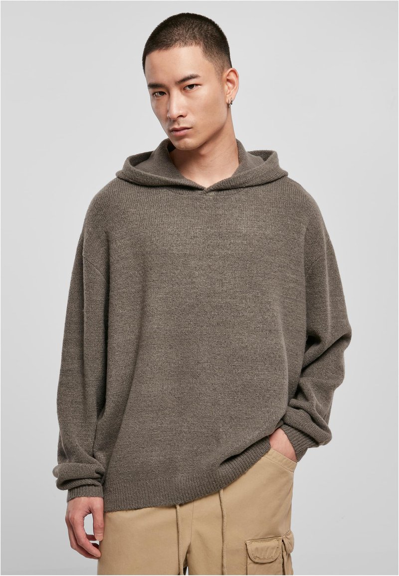 Oversized gray hoodie in soft fabric with a textured weave, featuring a drawstring hood and ribbed cuffs, paired with beige cargo pants.
