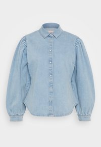 Lys blå denimskjorte med spiss krage, knapping foran og puffede ermer. Har buet hem og en jevn tekstur.