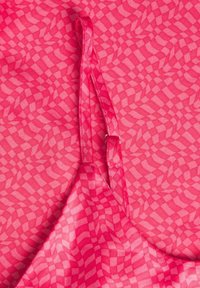 Różowa tkanina w wzór w kratkę. Posiada cienki pasek z metalowym regulatorem. Lekka, półprzezroczysta tekstura.