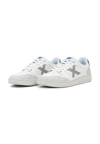 Baskets blanches avec une tige en cuir lisse, des accents en suède gris, une pointe perforée, un liseré bleu et un logo gris sur le côté.