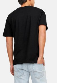 Schwarzes Baumwoll-T-Shirt mit kurzen Ärmeln, Rundhalsausschnitt und lockerer Passform. Die Rückansicht zeigt eine glatte Textur und einen geraden Saum.