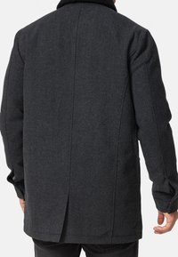 Mørkegrå uldfrakke med en struktureret overflade, der har en skræddersyet pasform, lange ærmer og en høj krave. Set bagfra vises sømdetaljer.