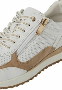 Valkoiset tennarit, joissa on rei'itetty nahka ja beige-nahkasuojus. Varustettu kultaisella vetskarilla ja teksturoidulla kumipohjalla tukemaan pitoa ja tukea.