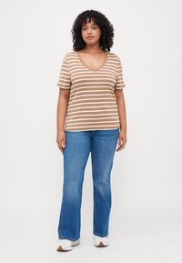 Camiseta de rayas marrón y beige en cuello en V, combinada con jeans azules de campana y sandalias blancas. Tela suave, mangas cortas, ajuste relajado.