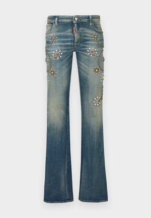 Blå denimjeans med vidde i benene har blomsterudsmykninger i forskellige farver samt nitter og palietter arrangeret i et dekorativt mønster.
