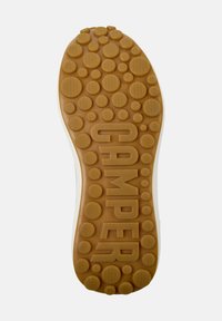 Suola di scarpa in gomma con superficie texturizzata. Presenta motivi circolari e il marchio impresso "CAMPER", colore marrone chiaro con bordo bianco.
