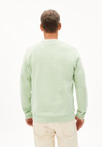 Sweatshirt vert menthe en coton doux, avec un col rond côtelé, des manches longues et un ourlet droit, présenté de dos.