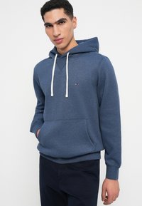 Μπλε φούτερ φτιαγμένο από μαλακό ύφασμα, με μπροστινή τσέπη, κουκούλα με κορδόνι και μικρό λογότυπο στο στήθος. Καθημερινή και άνετη εφαρμογή.