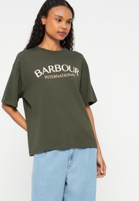 Πράσινο ελαιόλαδο cotton t-shirt με κοντά μανίκια, άνετη εφαρμογή, με μεγάλη κρεμ-χρωμη ένδειξη "BARBOUR INTERNATIONAL" στο στήθος.