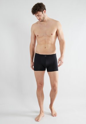 Schwarze Boxershorts in enganlicher Passform, aus glattem Material gefertigt, mit einem schlichten Design und einem elastischen Bund. Keine sichtbaren Muster oder Akzente.