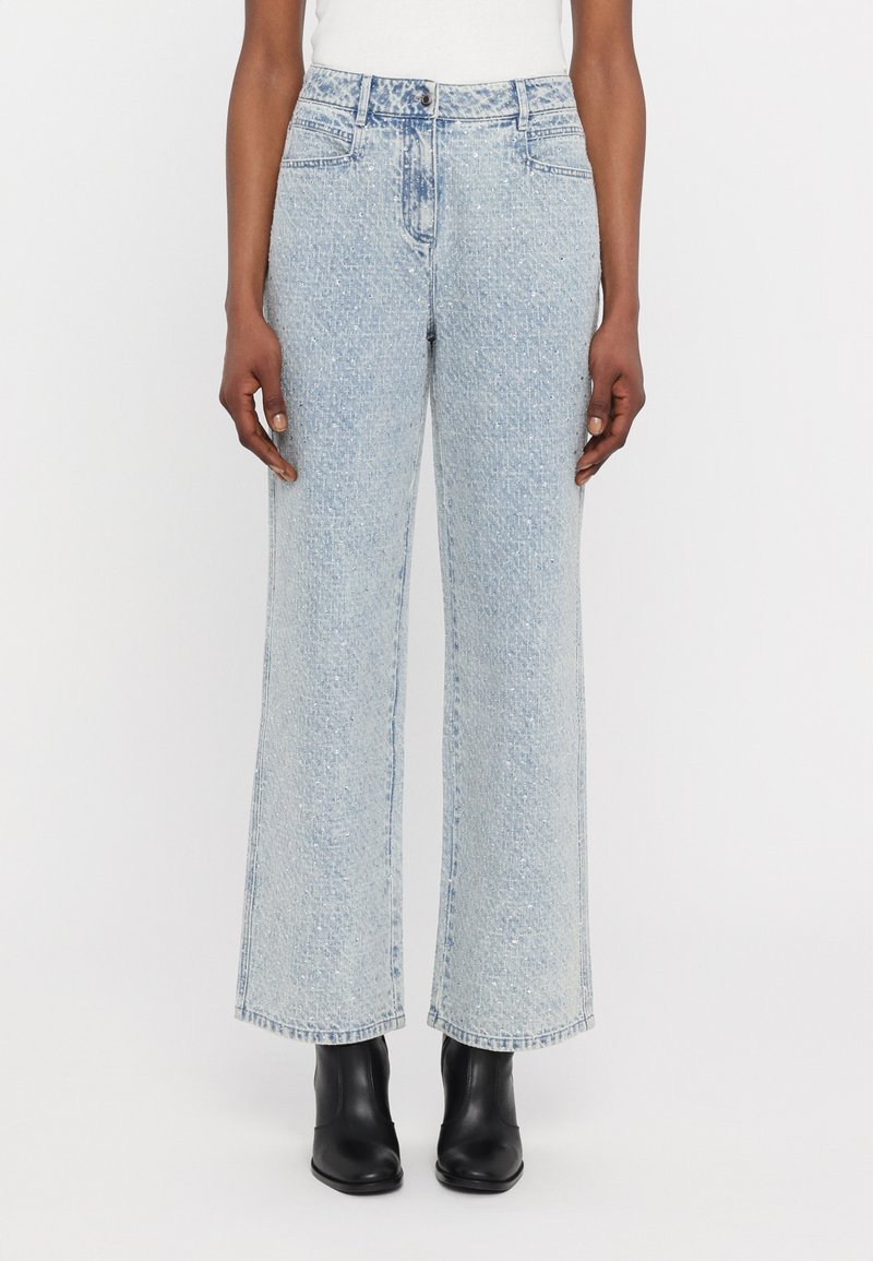 Hellblaue, weit geschnittene Jeans aus Denim mit dezenten Auswaschungen und geradem Schnitt, kombiniert mit schwarzen Knöchelstiefeln.