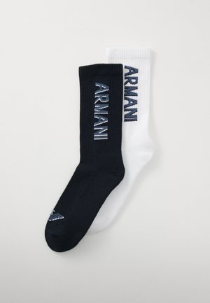 Chaussettes côtelées noir et blanc avec le logo "ARMANI" en couleurs contrastées, avec un petit détail rayé près de l'orteil de la chaussette noire.