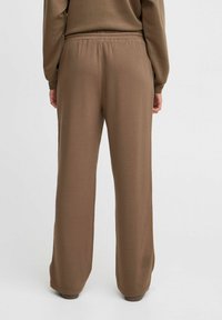 Ruske, loose-fitting lounge-housut elastisella vyötäröllä, valmistettu pehmeästä kankaasta. Suorat lahkeet, joissa on sileä rakenne, ilman taskuja tai kuvioita.