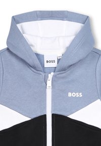 Hoodie in blauw, zwart en wit. Voorzien van een rits, geribbelde zoom en het "BOSS" logo aan de bovenhoek links. Gemaakt van zachte katoenen stof.