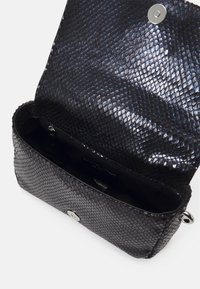 Sac en simili cuir serpent noir avec une finition texturée, fermeture magnétique et poche zippée à l'intérieur. Design compact et rectangulaire, intérieur lisse.