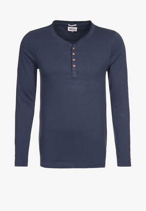 Laivastonsininen pitkähihainen Henley-paita, jossa on neljä ruskeaa nappia ja tikattu kaulussuunnittelu.