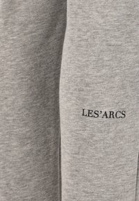 Graue Sweatpants aus einem glatten Stoff, mit "LES'ARCS" in Schwarz an der Seite bedruckt.