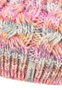 Multicolored chunky knit fabric with a braided pattern and a small beige tag labeled "Sterntaler" sewn into the edge.