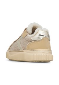 Beige sneaker with soft textile upper, metallic gold accents, fur-lined collar, and ridged rubber sole. Velcro strap for closure.