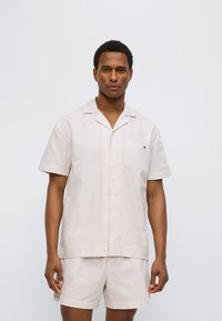 Σετ πιτζάμες με κοντό μανίκι, ριγωτό σε μπεζ και λευκό, με τσέπη, κουμπιά μπροστά και απαλό ύφασμα.