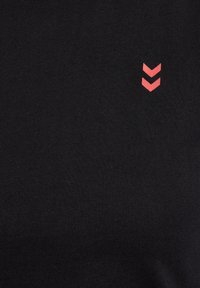 Zwart T-shirt van zacht materiaal met een klein rood chevronlogo aan de linkerkant. Het ontwerp is simpel en strak.