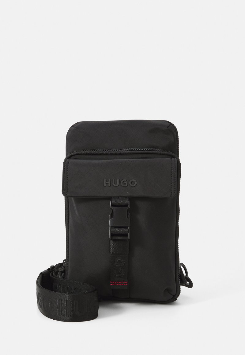Svart crossbody-veske med glidelås og justerbar stropp. Har en frontlomme og et HUGO-logo embossert på klaffen.
