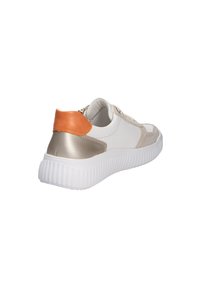 Baskets blanches avec des accents beige et argent métallique, dotées d'une languette de talon orange et d'une semelle blanche épaisse à nervures, vues de l'angle arrière latéral.