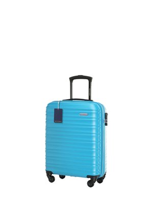 Niebieska walizka na twardej skorupie z czterema czarnymi obrotowymi kółkami, czarną teleskopową rączką i niebieską zawieszką bagażową.