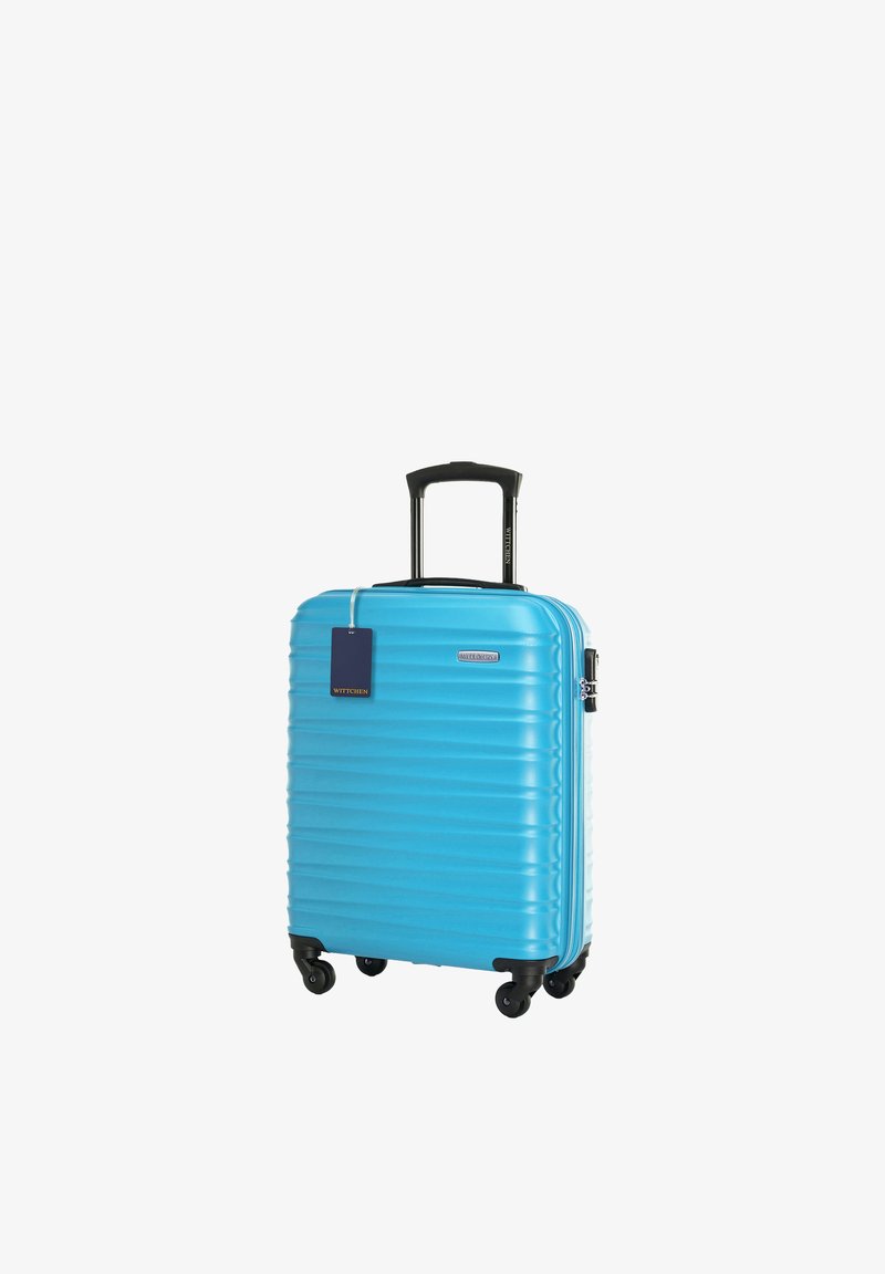 Niebieska walizka na twardej skorupie z czterema czarnymi obrotowymi kółkami, czarną teleskopową rączką i niebieską zawieszką bagażową.